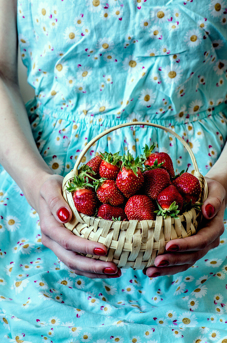 A woman holding a basket of fresh strawberries