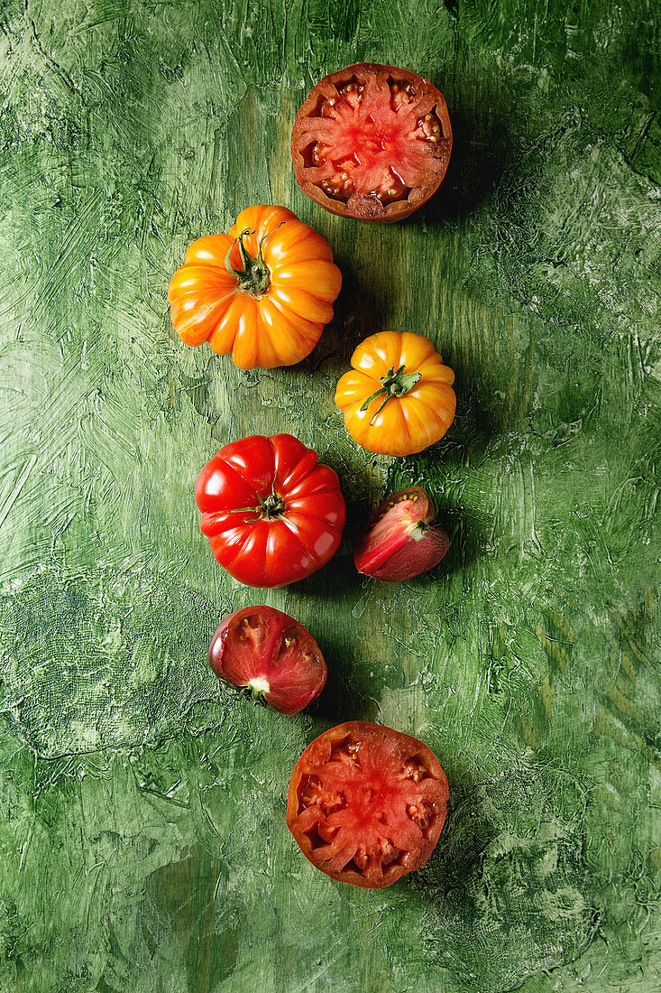 Gelbe und rote Bio-Tomaten, ganz und aufgeschnitten (Aufsicht)