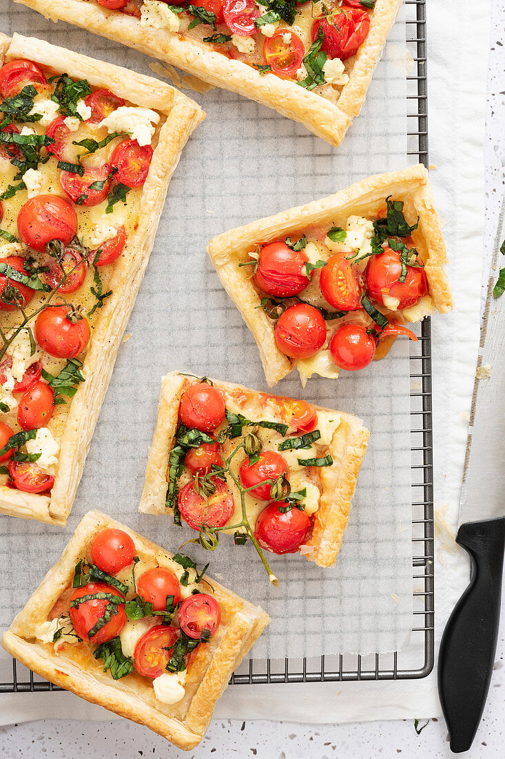 Tomato, basil and boccocini tarts with cut pieces on a wire rack