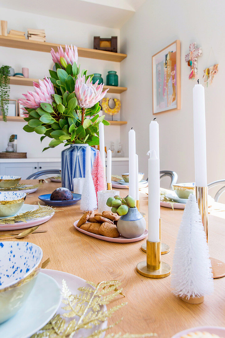 Kerzen und Blumen als Centerpiece auf gedecktem Tisch