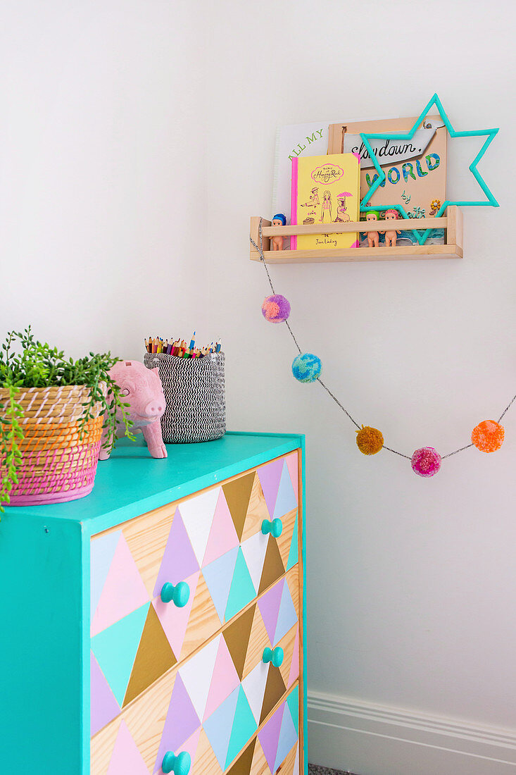 Chest of drawers painted with pastel colored triangle pattern in children's room