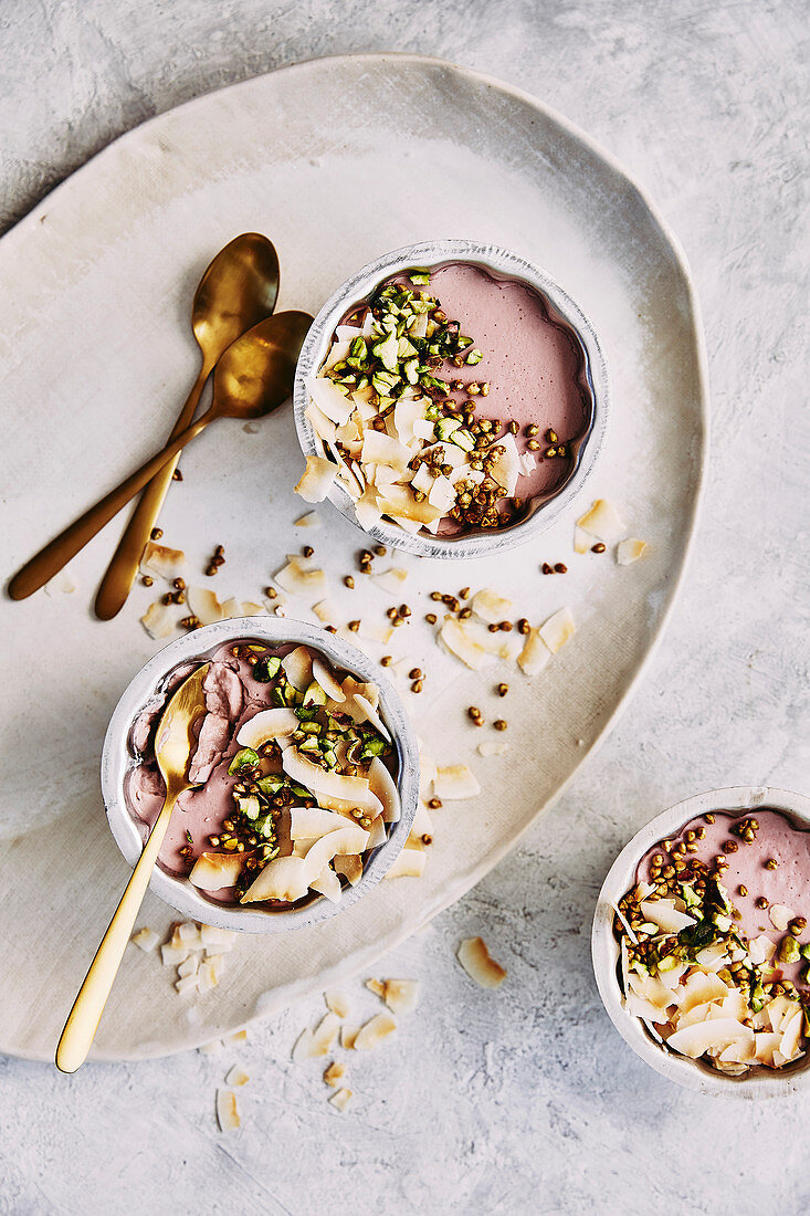 Dairy free raspberry and coconut milk panna cotta dessert, topped with buckweat, toasted coconut and pistachio nuts