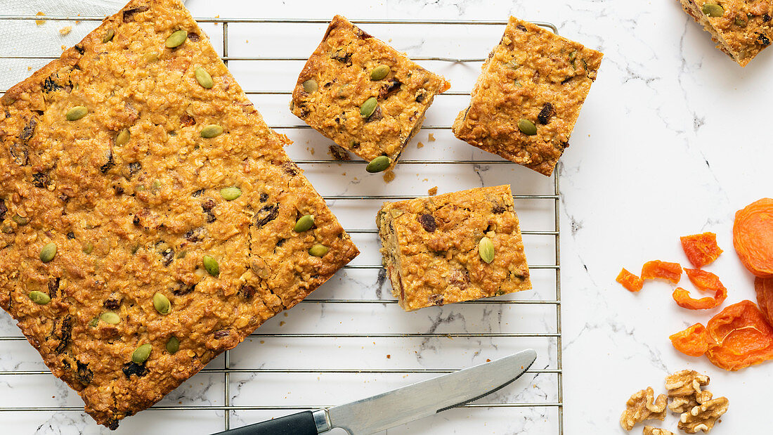 Apricot, pumpkin seed and oatmeal slice cut into pieces, cooling on a wire rack with of dried apricots and walnuts