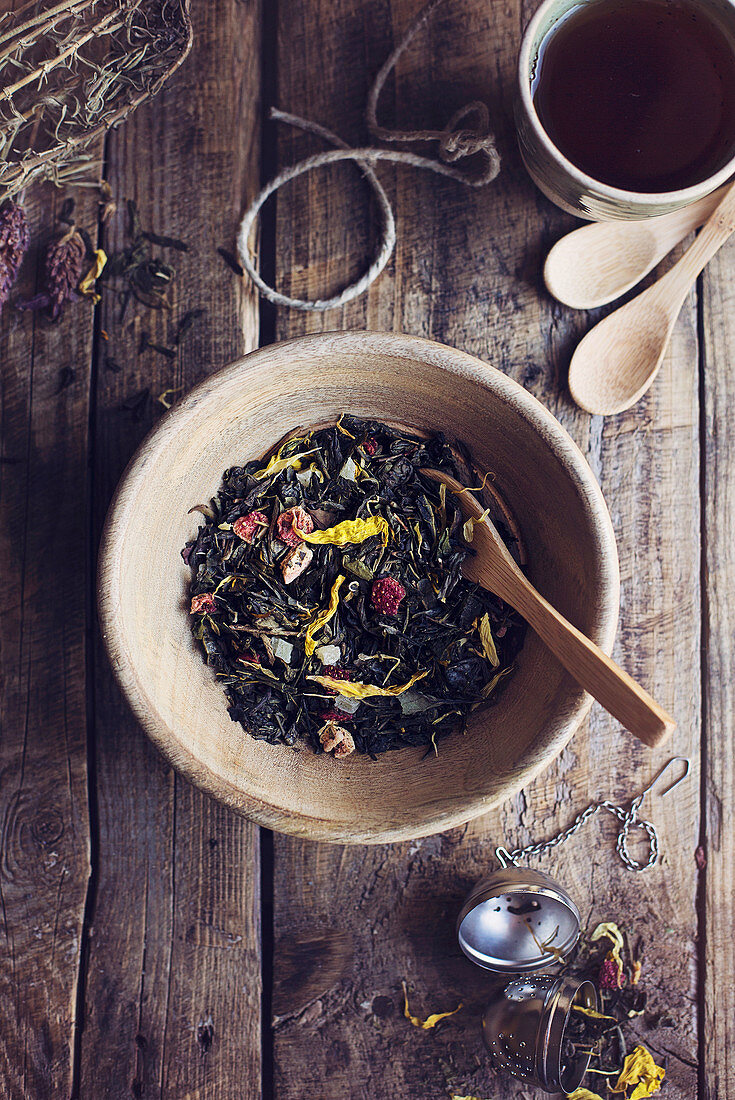 Herbal dry tea leaves with wild flowers and dried fruit on wooden rustic table