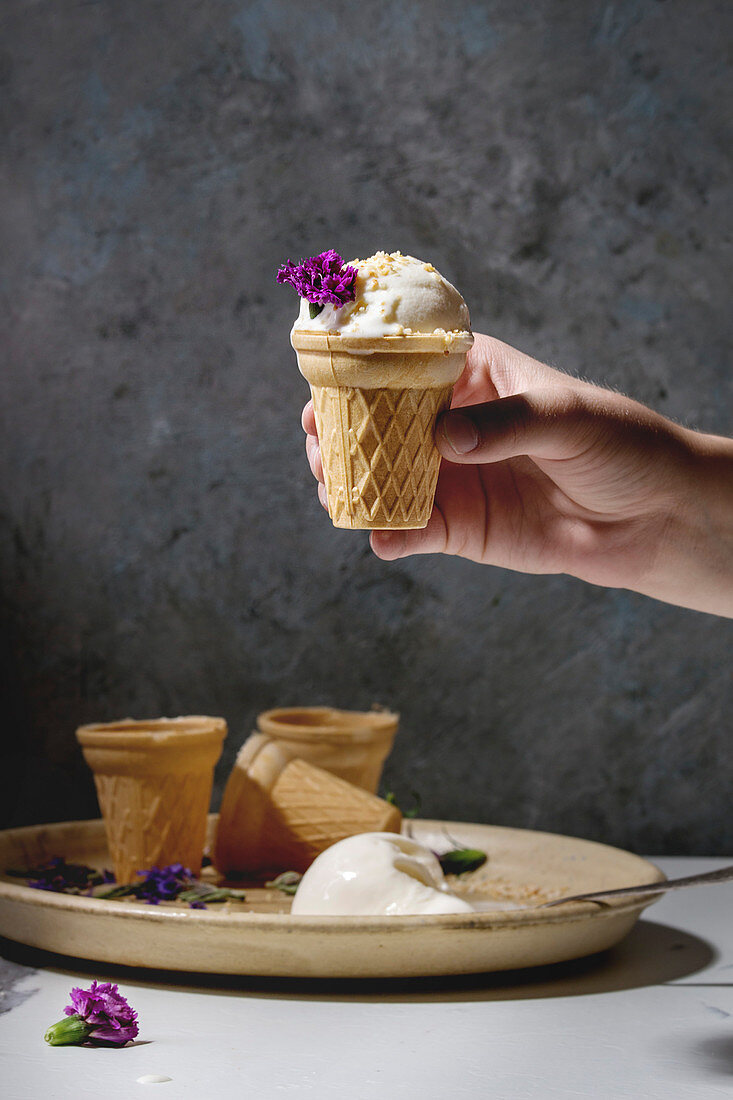 Child s hand take homemade vanilla ice cream in small waffle cup