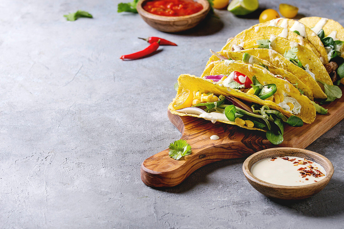 Variety of vegetarian corn tacos with vegetables, green salad, chili pepper