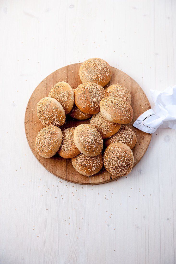 Sesame buns (burger rolls) on a round wooden board