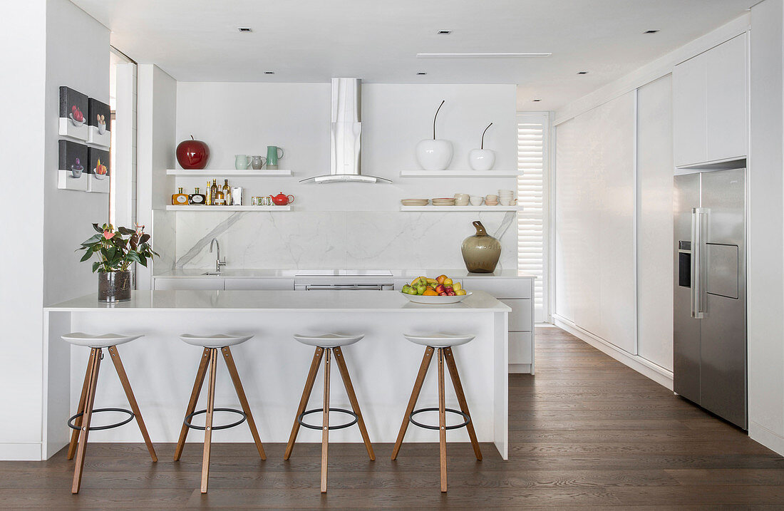 Counter and barstools in white, open-plan kitchen