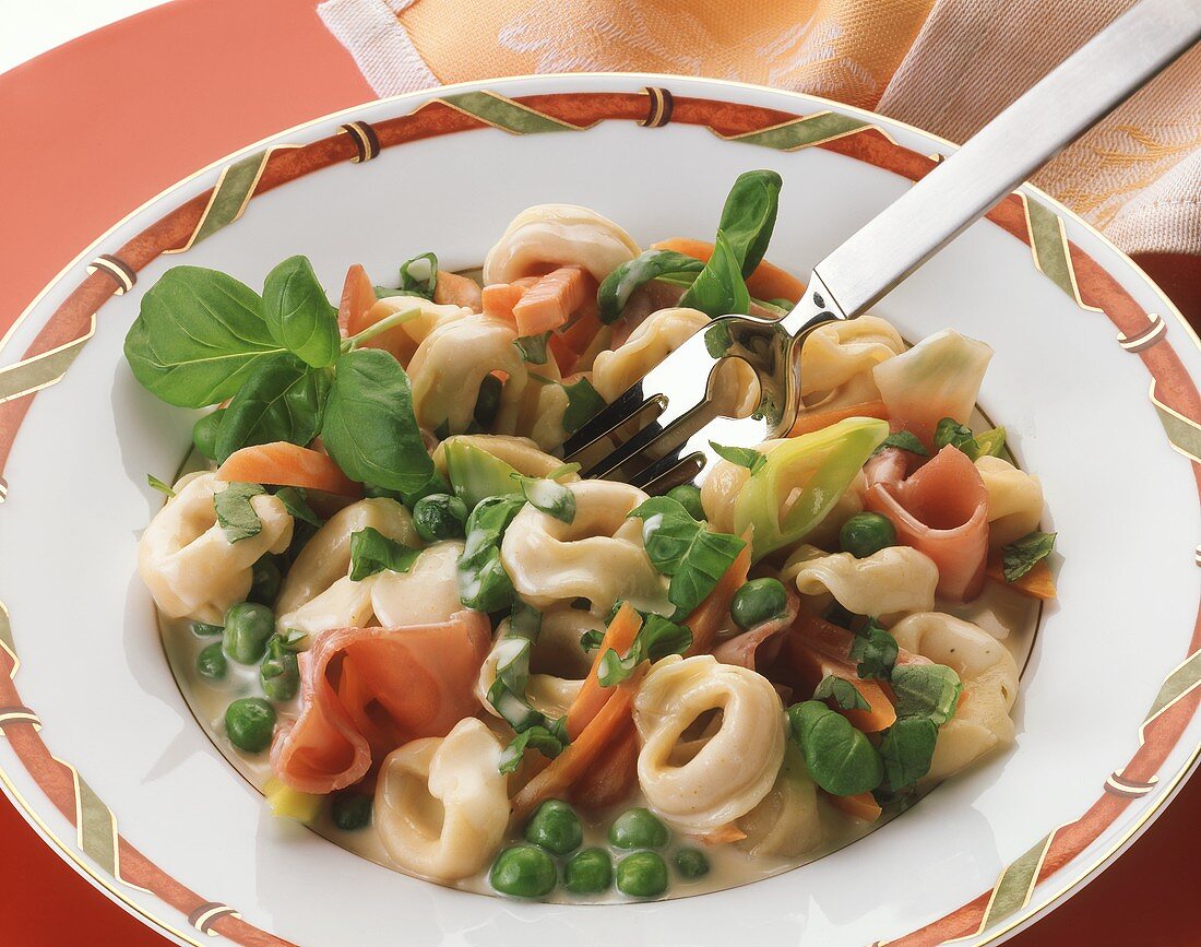 Tortellini with mixed vegetables, ham and basil
