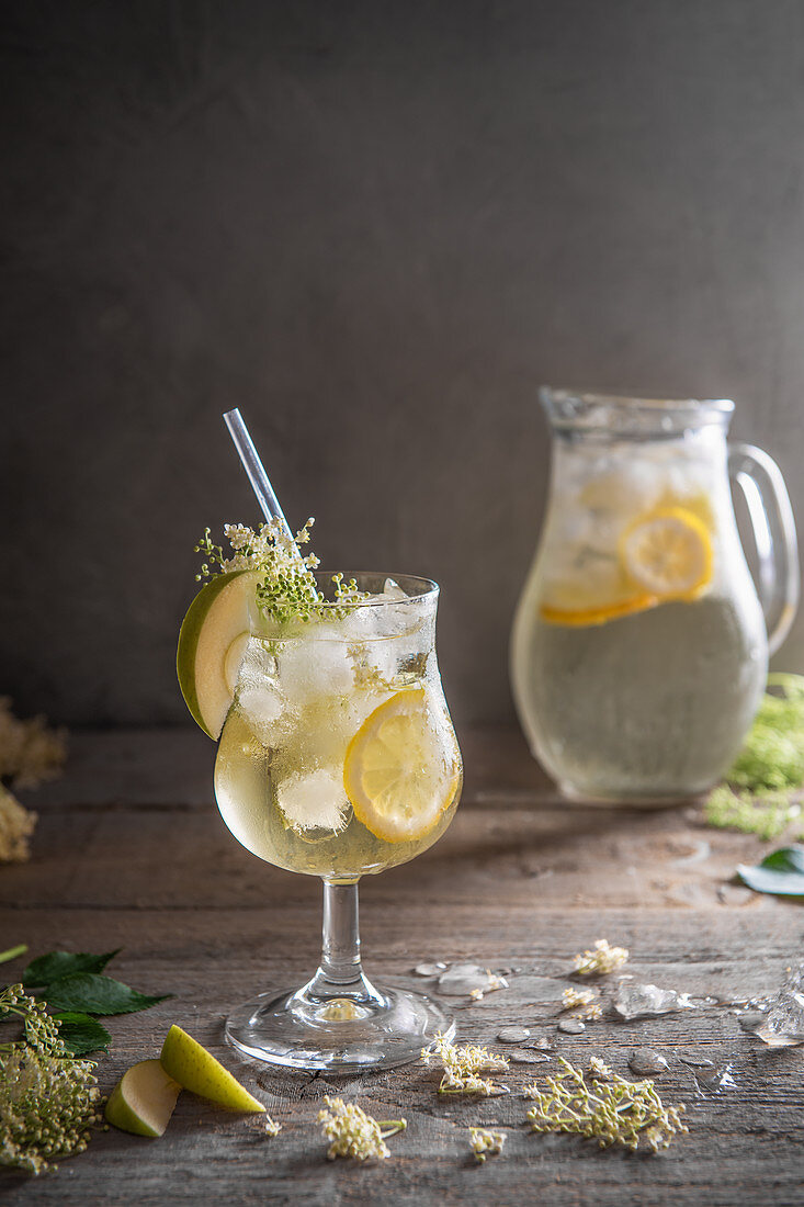 Holunder-Cordial mit Zitronen, Apfelscheiben und Eiswürfeln