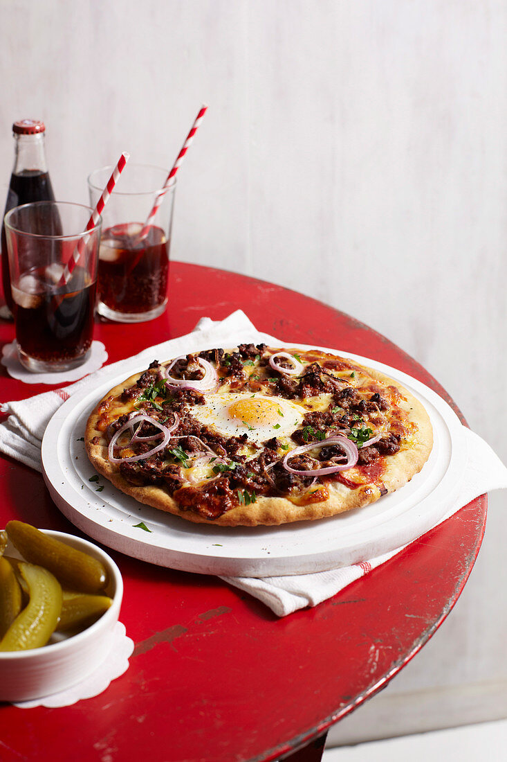 Pizza im Burger-Stil mit Spiegelei und Zwiebeln