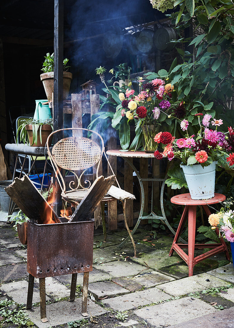 Feuerkorb vor Gartentischen mit Blumensträußen