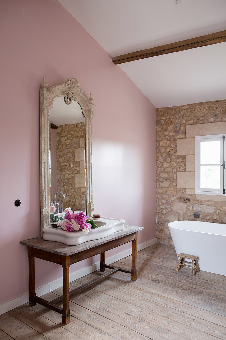Waschbecken mit Pfingstrosen vor Antikspiegel an rosa Wand im Badezimmer