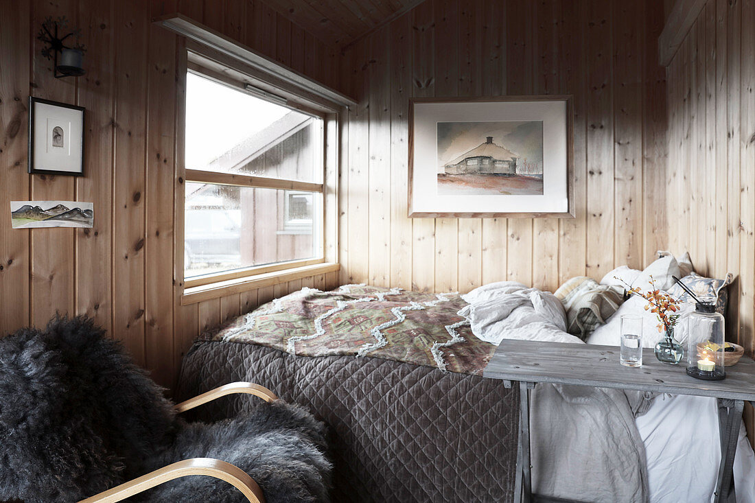 Double bed and panelled walls in cosy bedroom