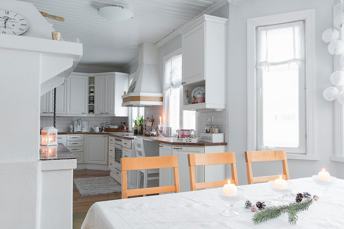 Christmas decorations on dining table and white kitchen in open-plan interior