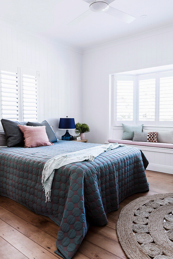 Double bed with quilt in white bedroom