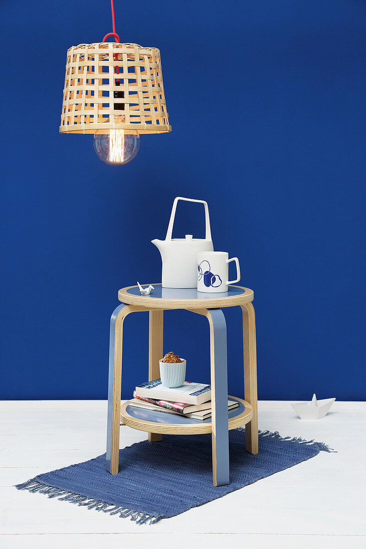 Side table with shelf made from stool in front of royal-blue wall
