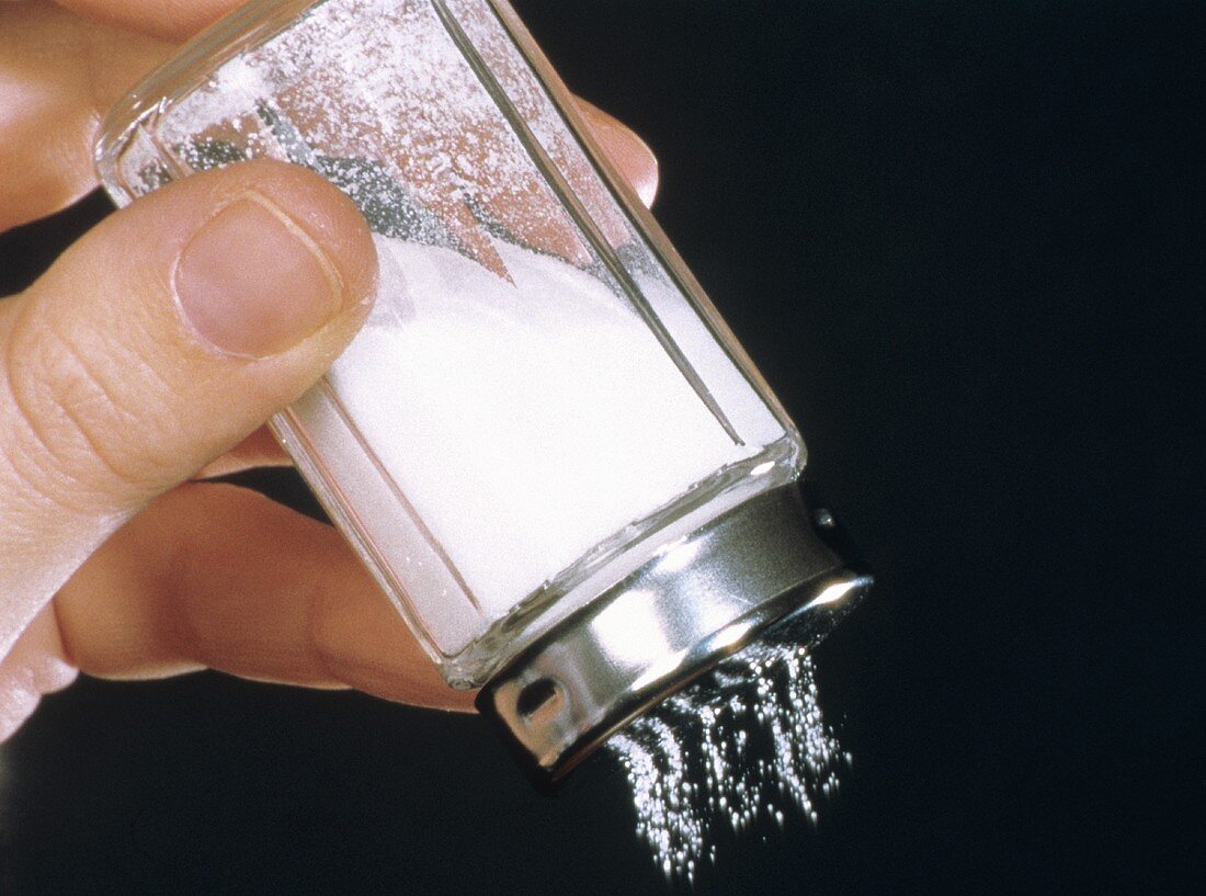 Hand streut Salz aus Salzstreuer