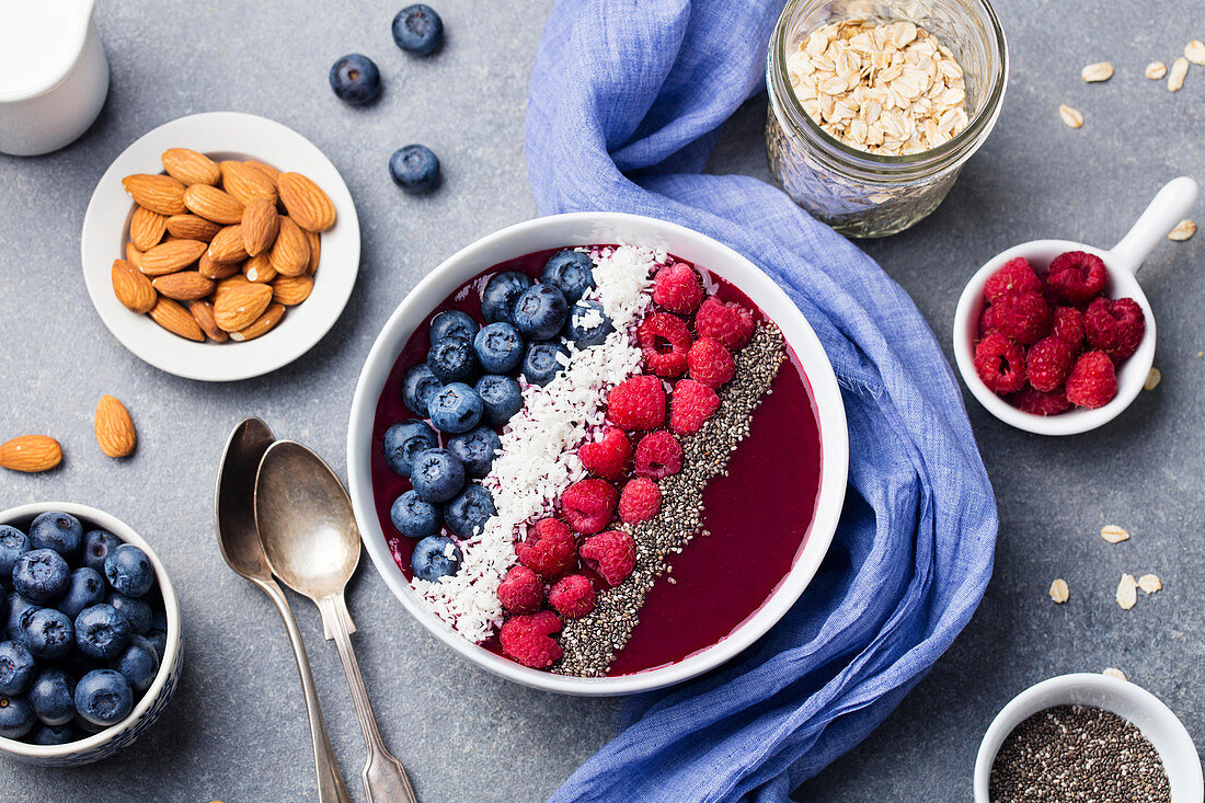 Smoothie bowl with fresh raspberry, blueberry, coconut flakes and chia seeds