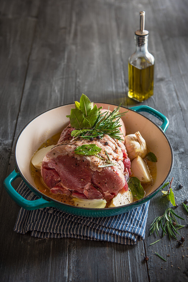 Bratfertige Schweineschulter mit schwarzem Pfeffer, frischen Kräutern, Knoblauch, Zwiebeln und Olivenöl