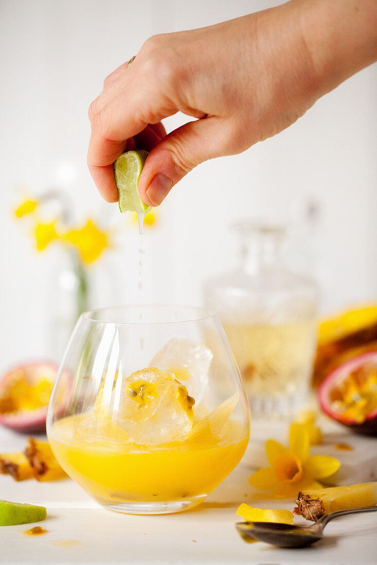 Gin Tonic mit Ananas- und Passionsfruchtsaft, Limettensaft zufügen