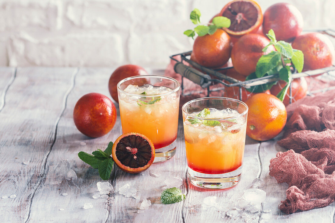 Alcohol tequila sunrise cocktail with red orange, ice and mint