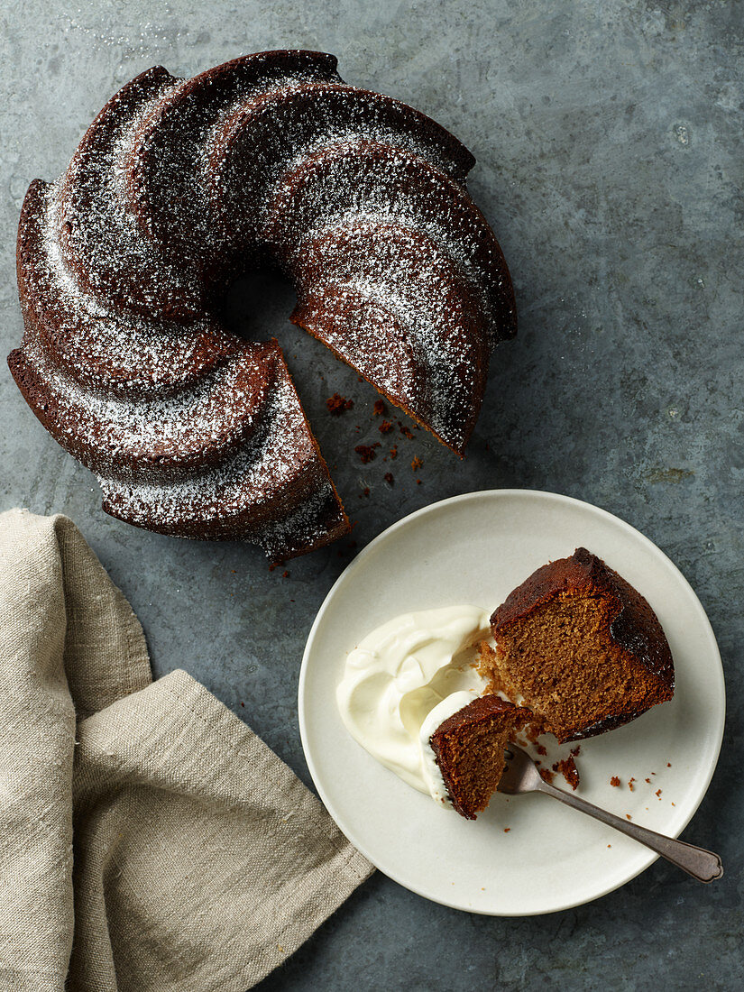 A slice of Bundt cake served with cream on a cake plate