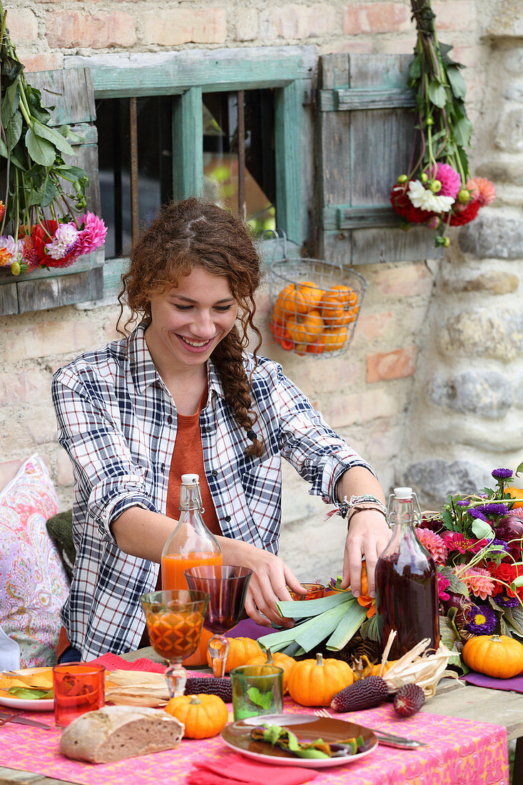 Young woman at table set for harvest festival in bright colours