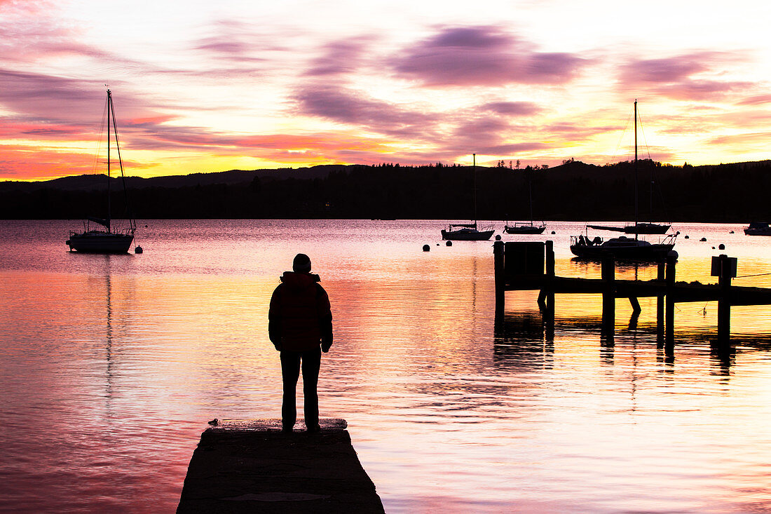A man watches the sunset at Waterhead, UK
