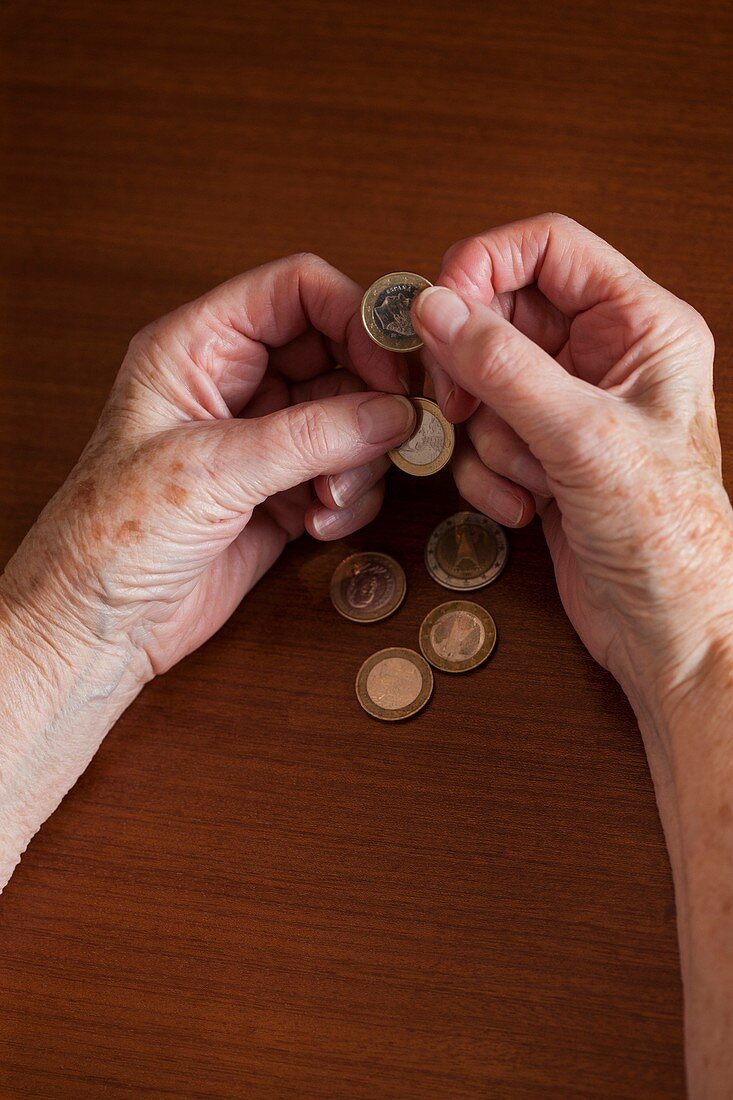 Elderly woman counting Euro coins in her hands