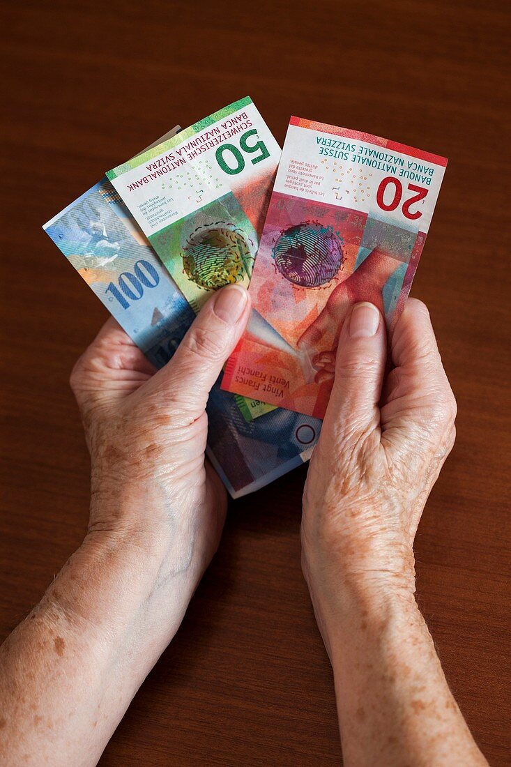 Elderly woman holding Swiss banknotes