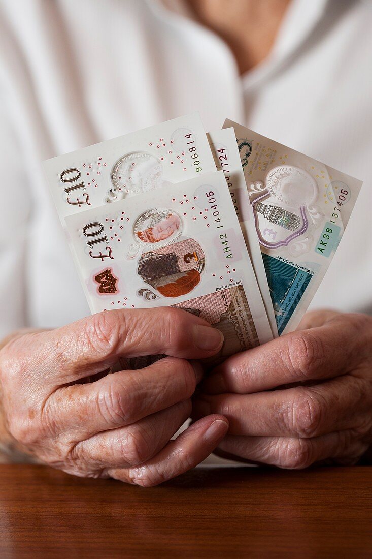 Close-up of elderly woman holding British banknotes
