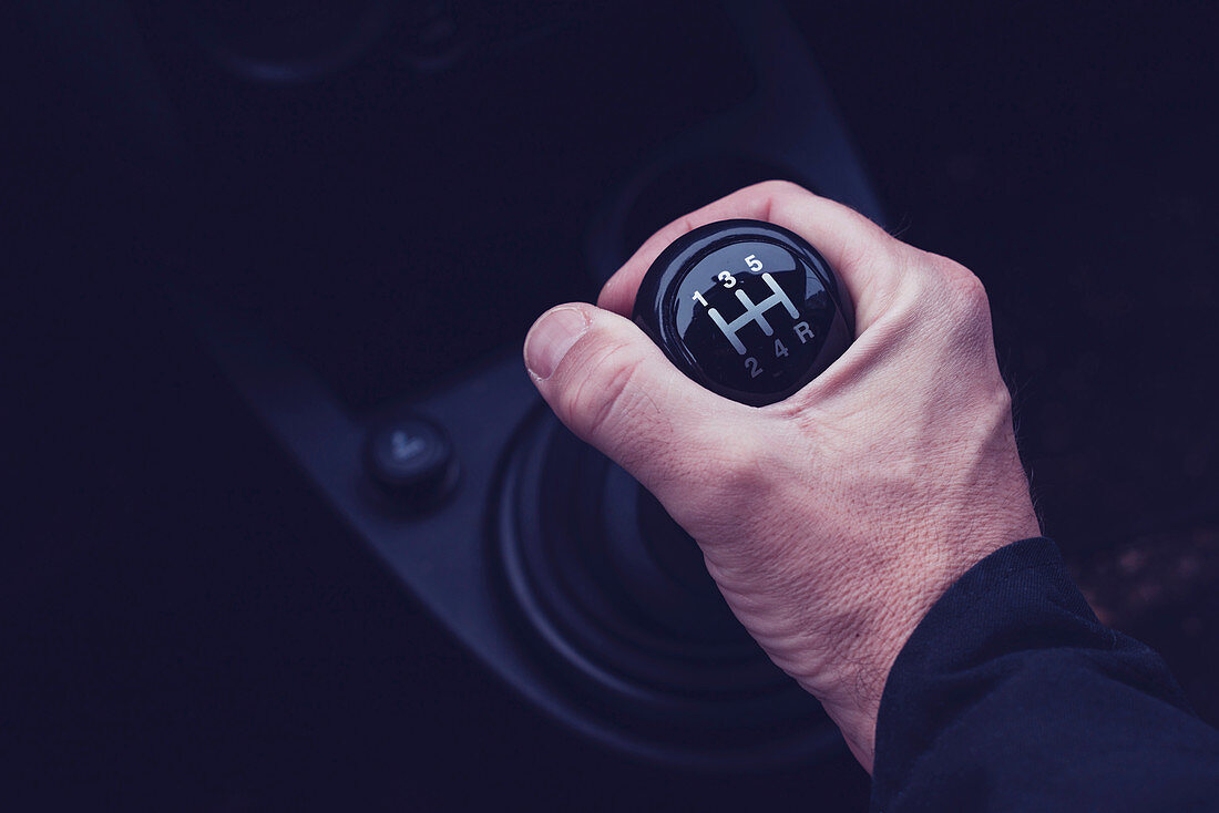 Male hand changing gear in a car