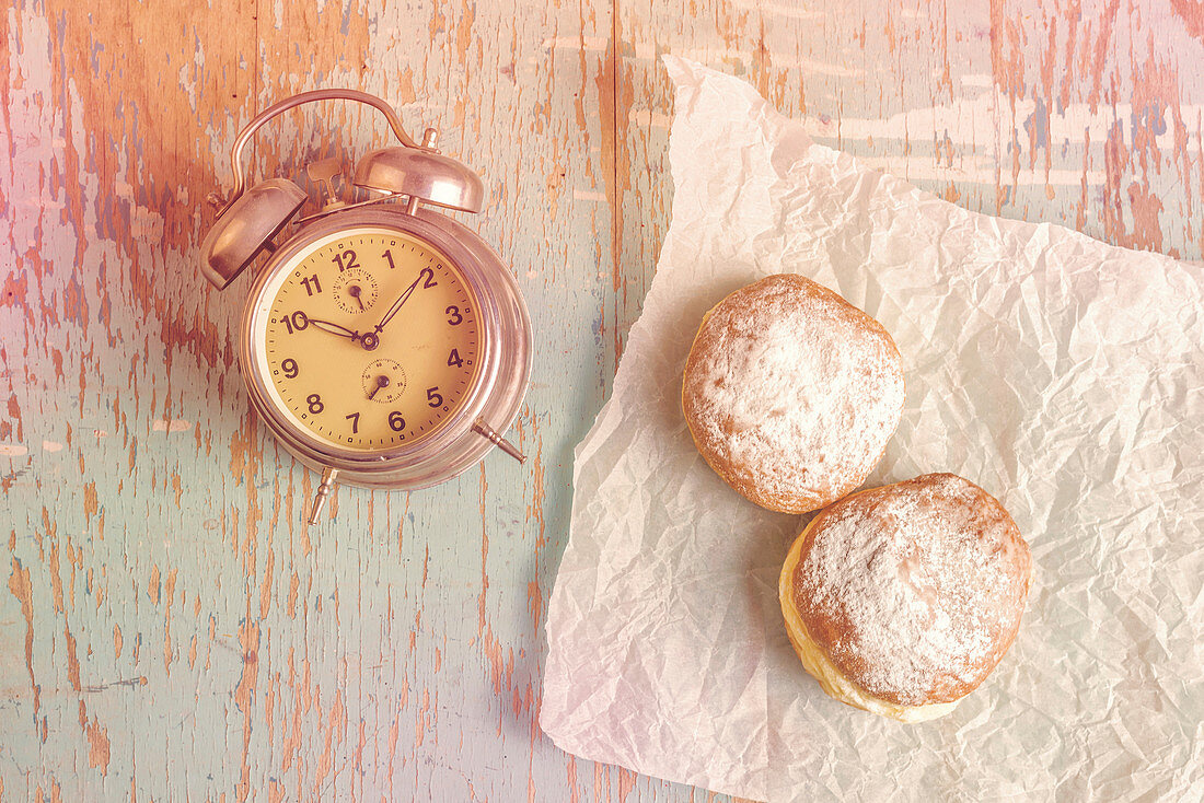 Donuts and vintage clock on rustic table