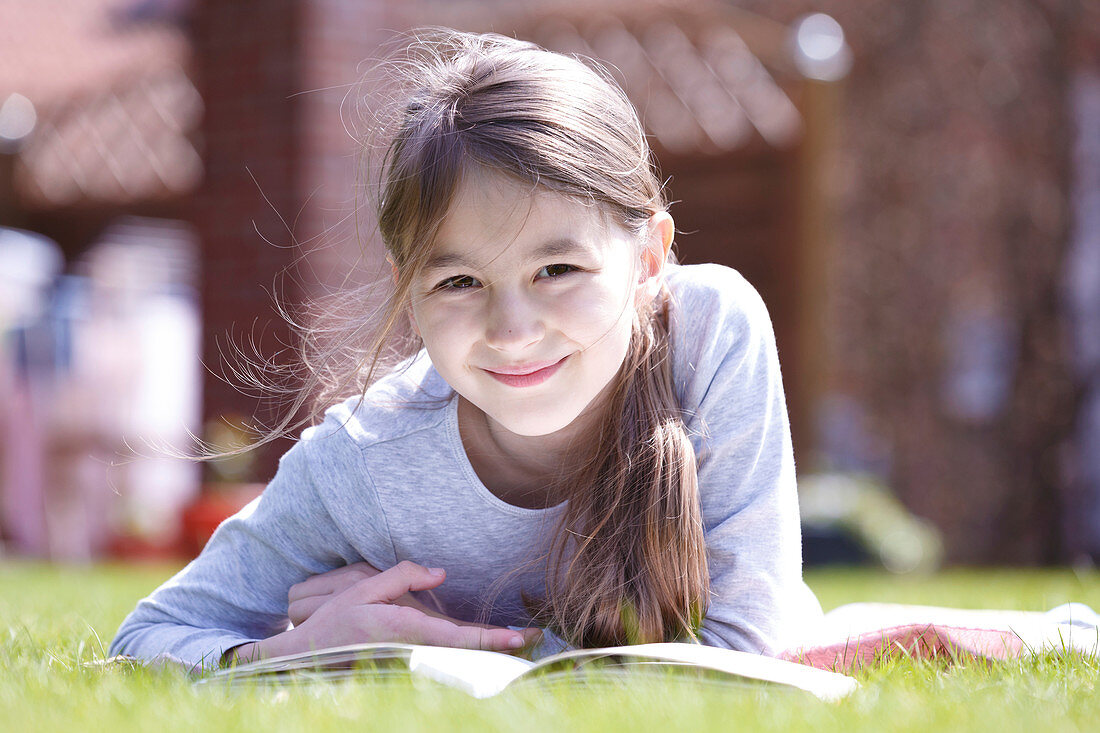 Girl lying on grass reading