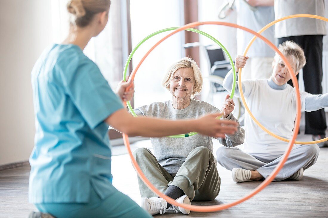 Physiotherapist with women holding plastic hoops