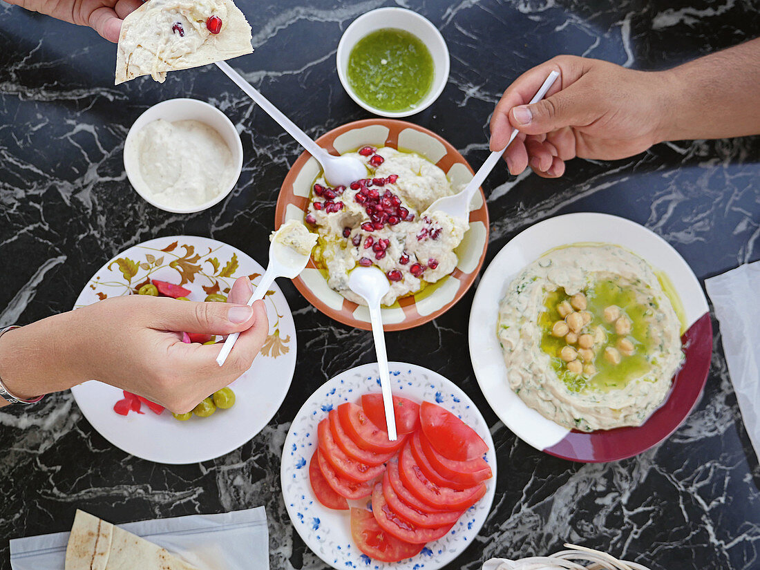 Menschen essen zusammen gemischte arabische Vorspeisen mit Fladenbrot