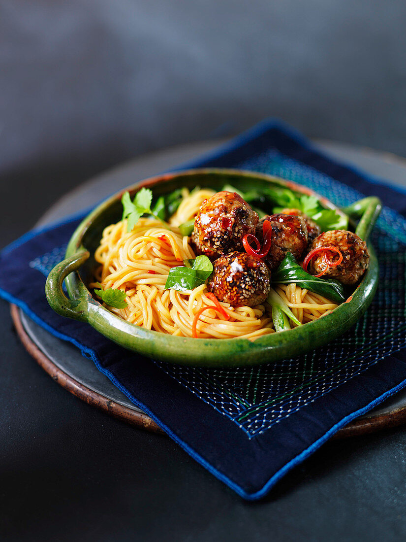 Meatballs with noodles, vegetables, and sesame seeds