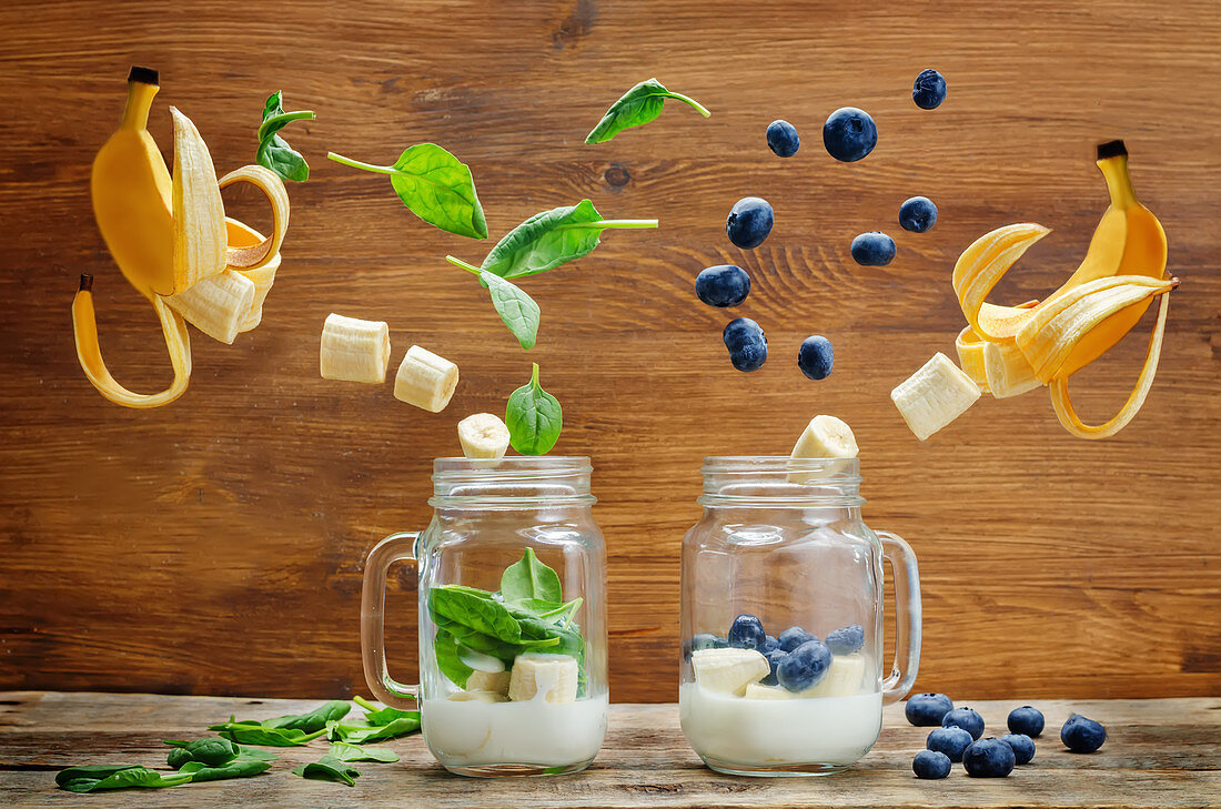 Spinach banana and blueberry banana smoothie with flying slices on a wood background