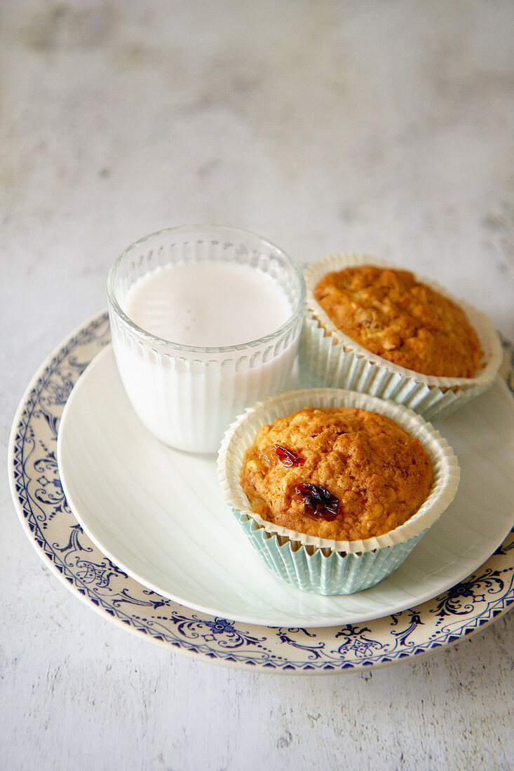 Muffins with raisins next to a glass of milk