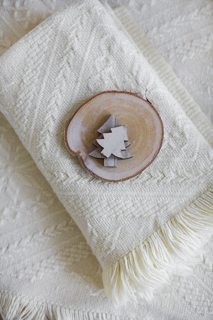 Deko-Tannenbäumchen und eine Baumscheibe auf einer Wolldecke