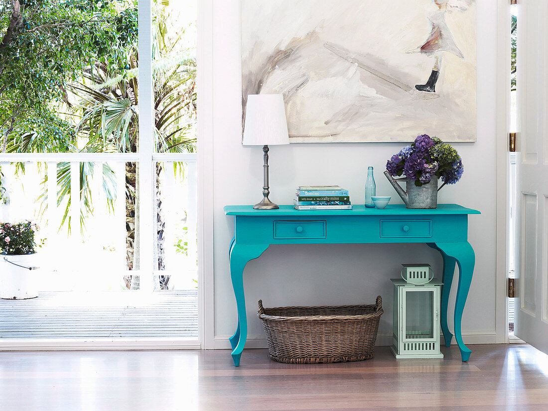 Turquoise blue lacquered table with hydrangeas, books and table lamp