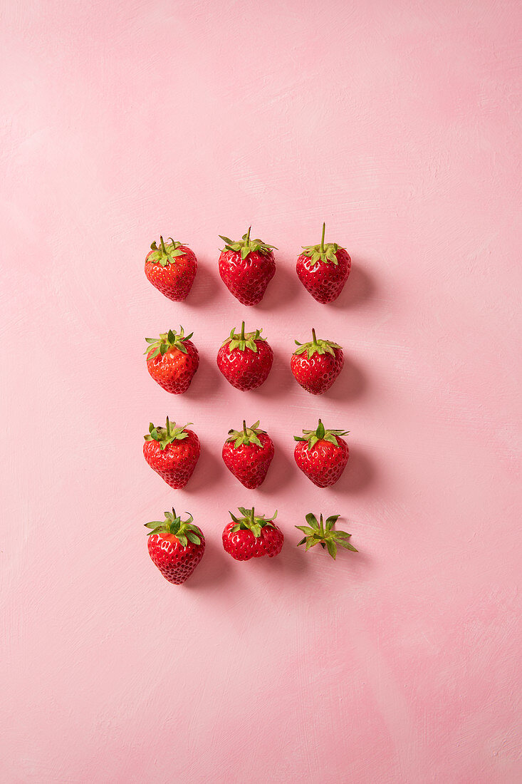 Erdbeeren liegen in Reih und Glied, eine Erdbeere angebissen