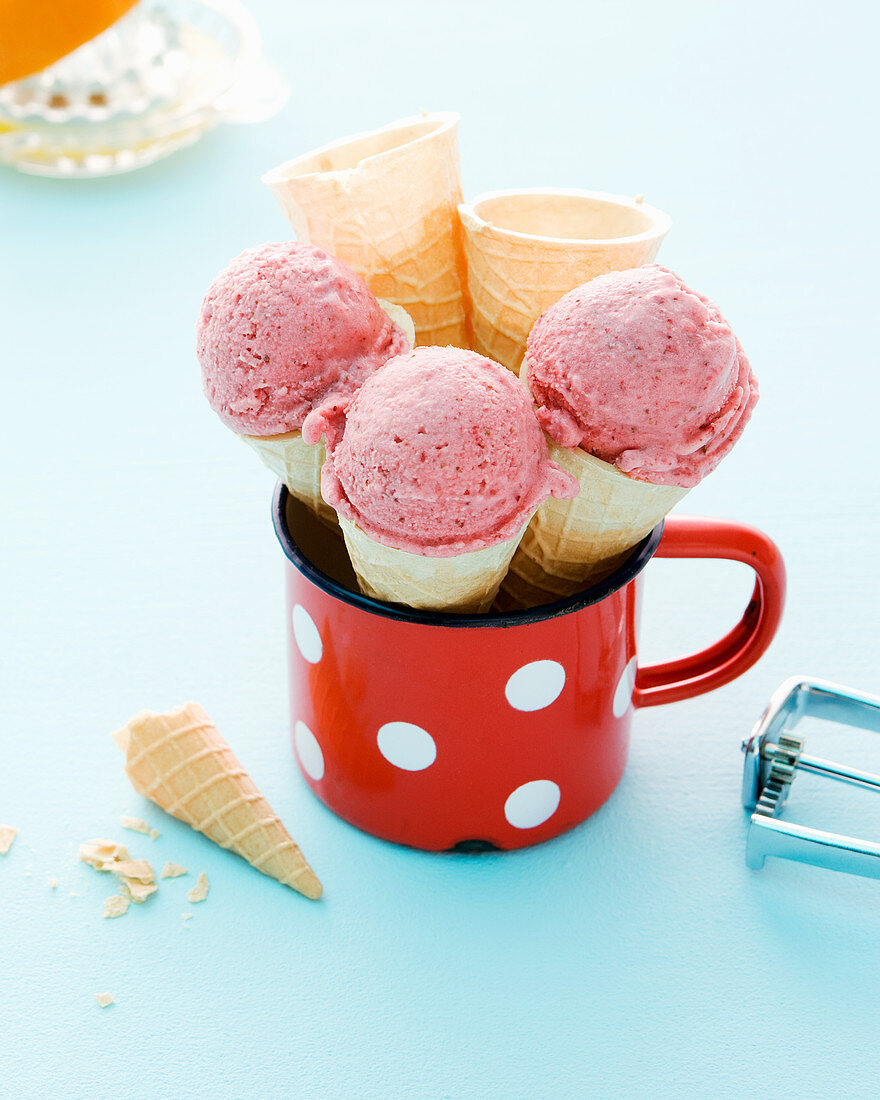 Homemade strawberry ice in cones and an enamel mug