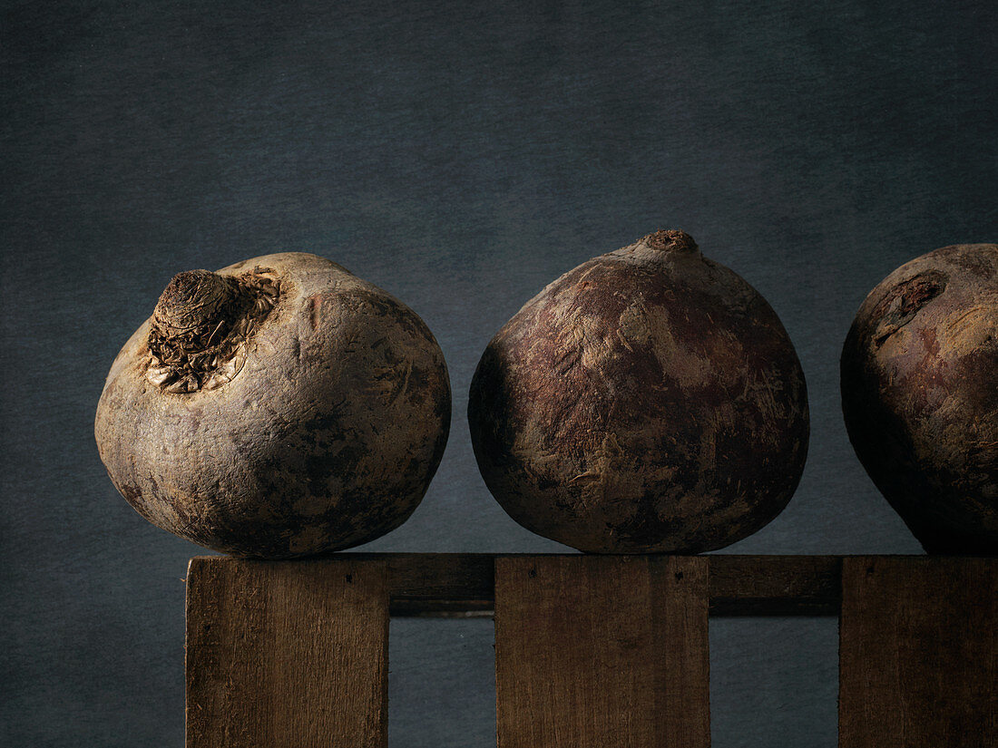 Three red beets on a wooden frame