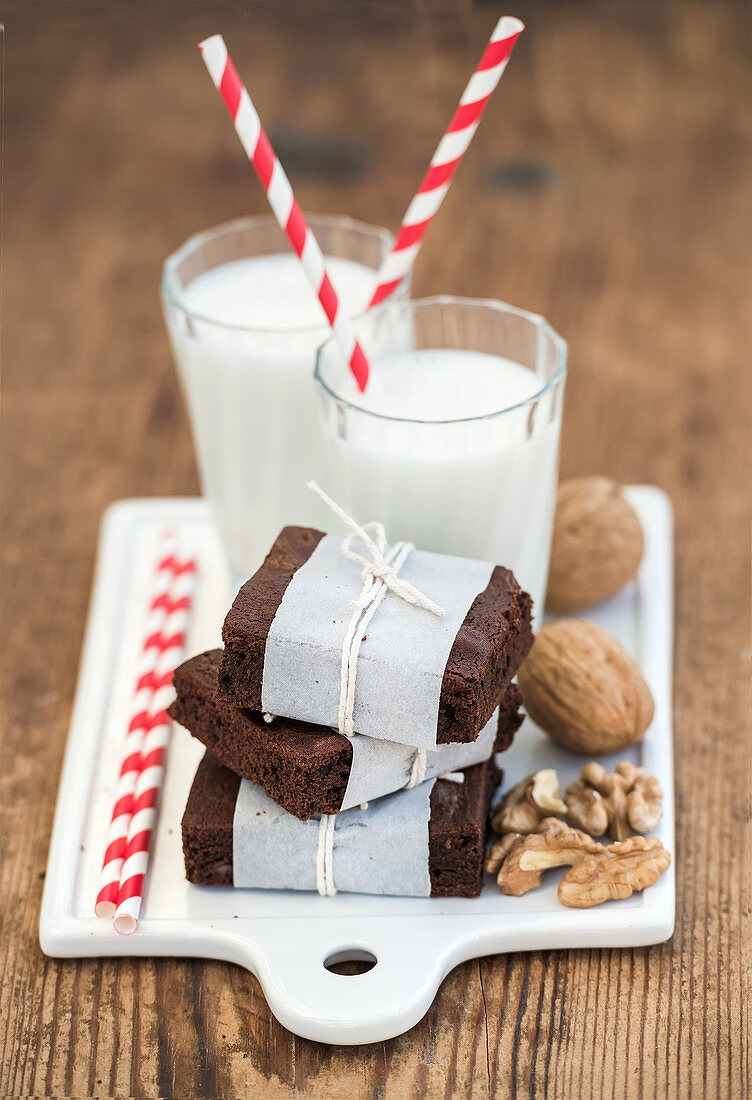 Brownies in Papier gewickelt serviert mit Nüssen und Milch in Gläsern
