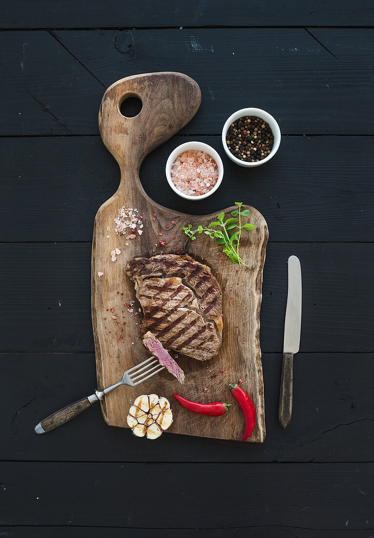 Gegrilltes Rib Eye Steak mit Kräutern und Gewürzen auf Holzbrett