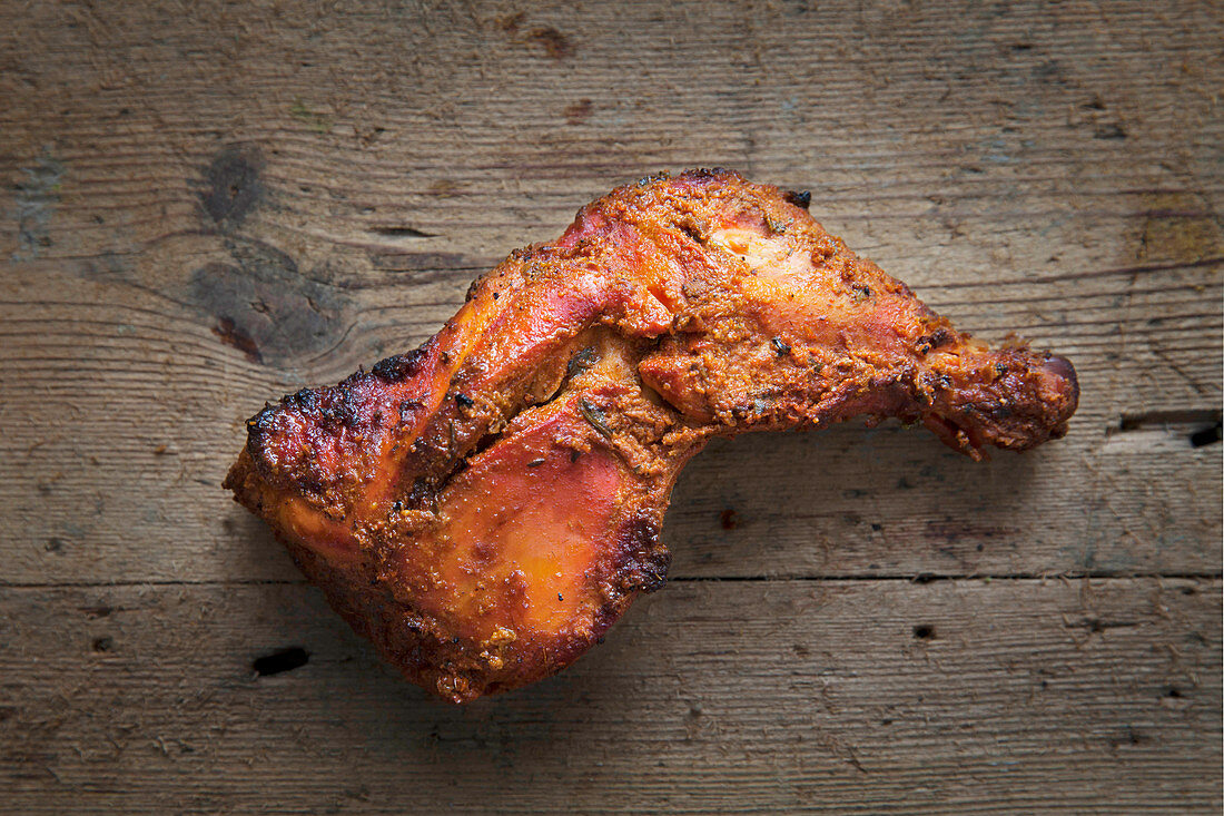 Tandori chicken leg on a wooden background