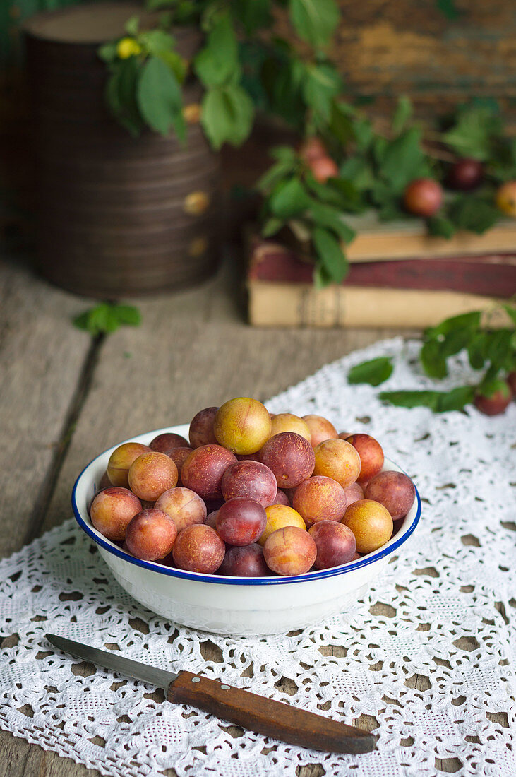 Fresh mirabelle plums in white bowl on a rustic wooden table