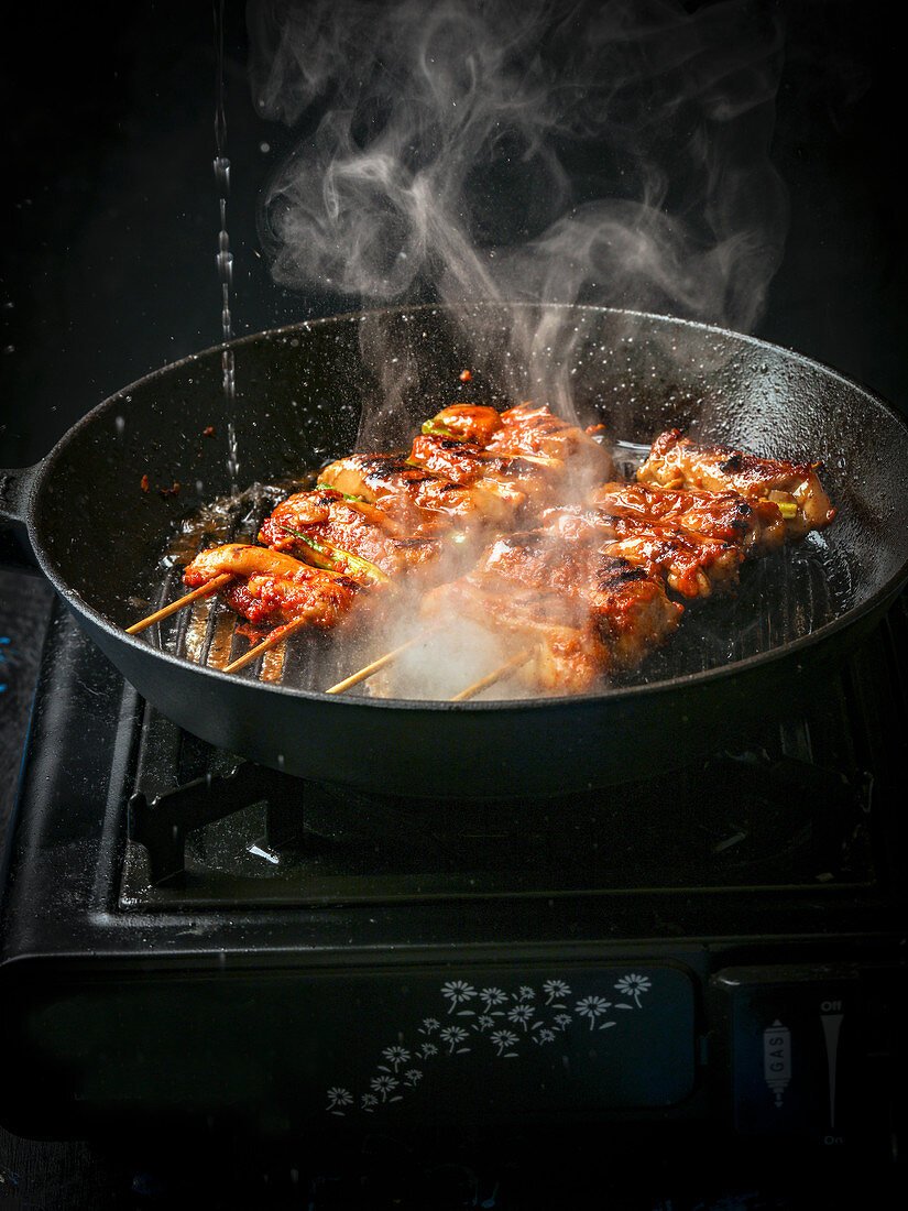 Steaming chicken skewers in a grill pan